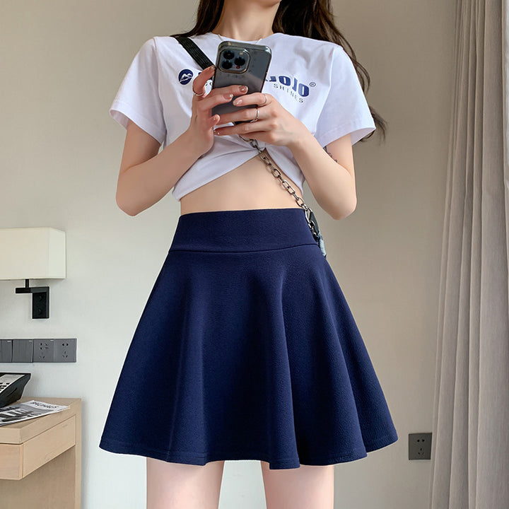 The new pleated skirt is paired with a loose white shirt featuring a tie-back detail.
